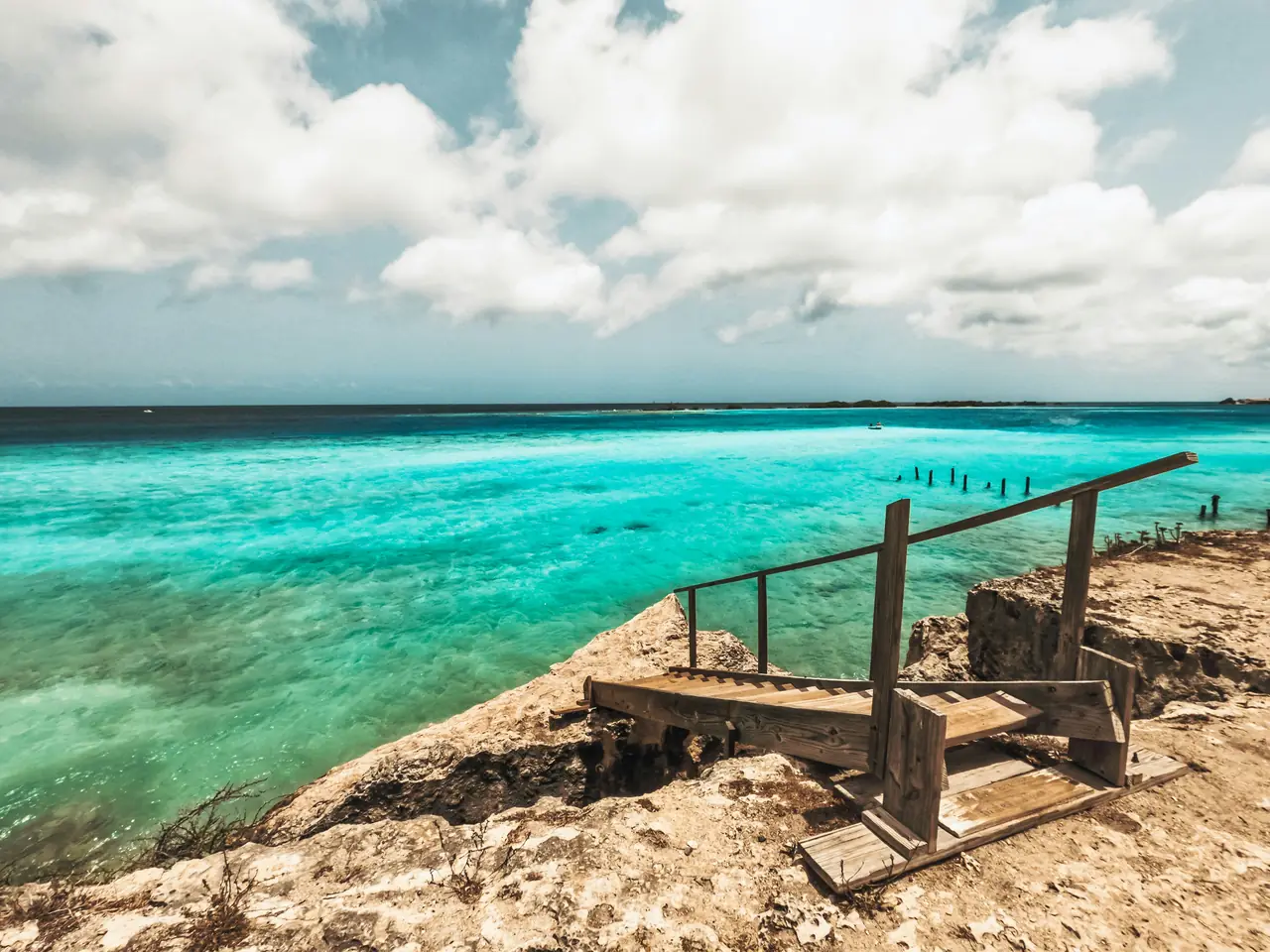 A wooden jetty running out over clear turquoise Caribbean water