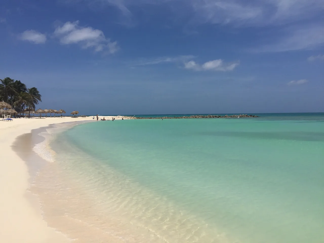 A long curve of pale sand meeting flat pale-green shallows on Eagle Beach, Aruba