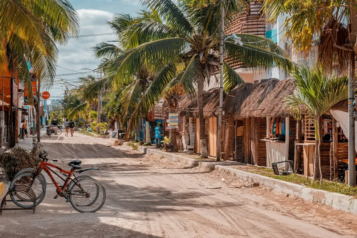 A sandy main street on Isla Holbox with bicycles, palms and low wooden buildings