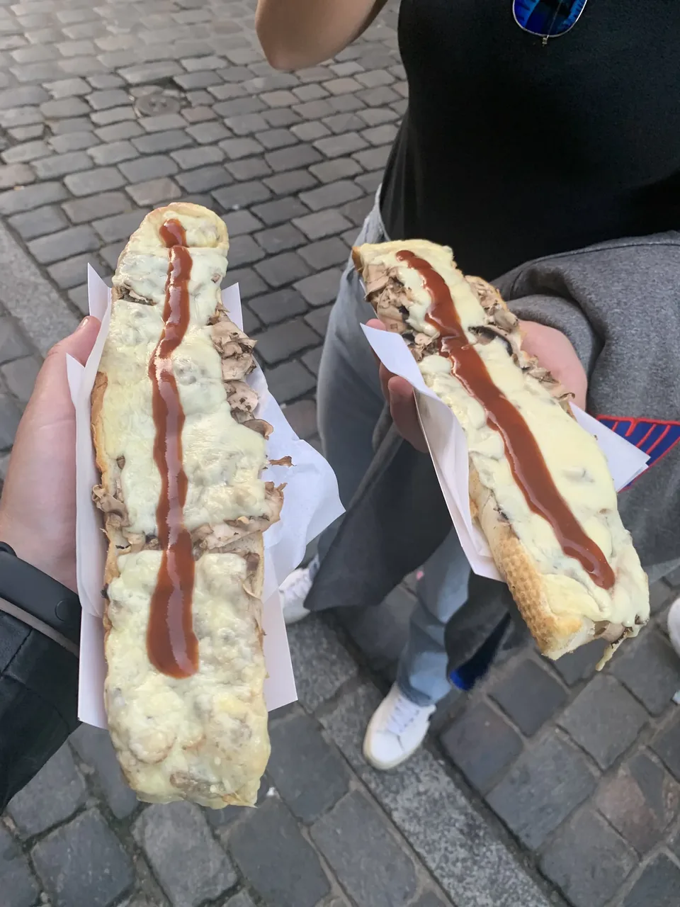 Two long baked zapiekanki held in hand at a Kraków street food stall