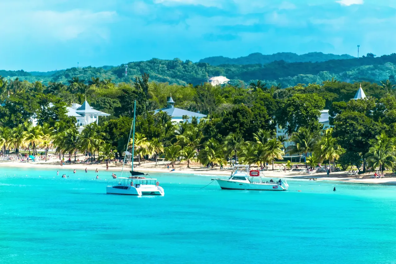 Boats moored in turquoise water off Montego Bay with green hills and hotels along the shore