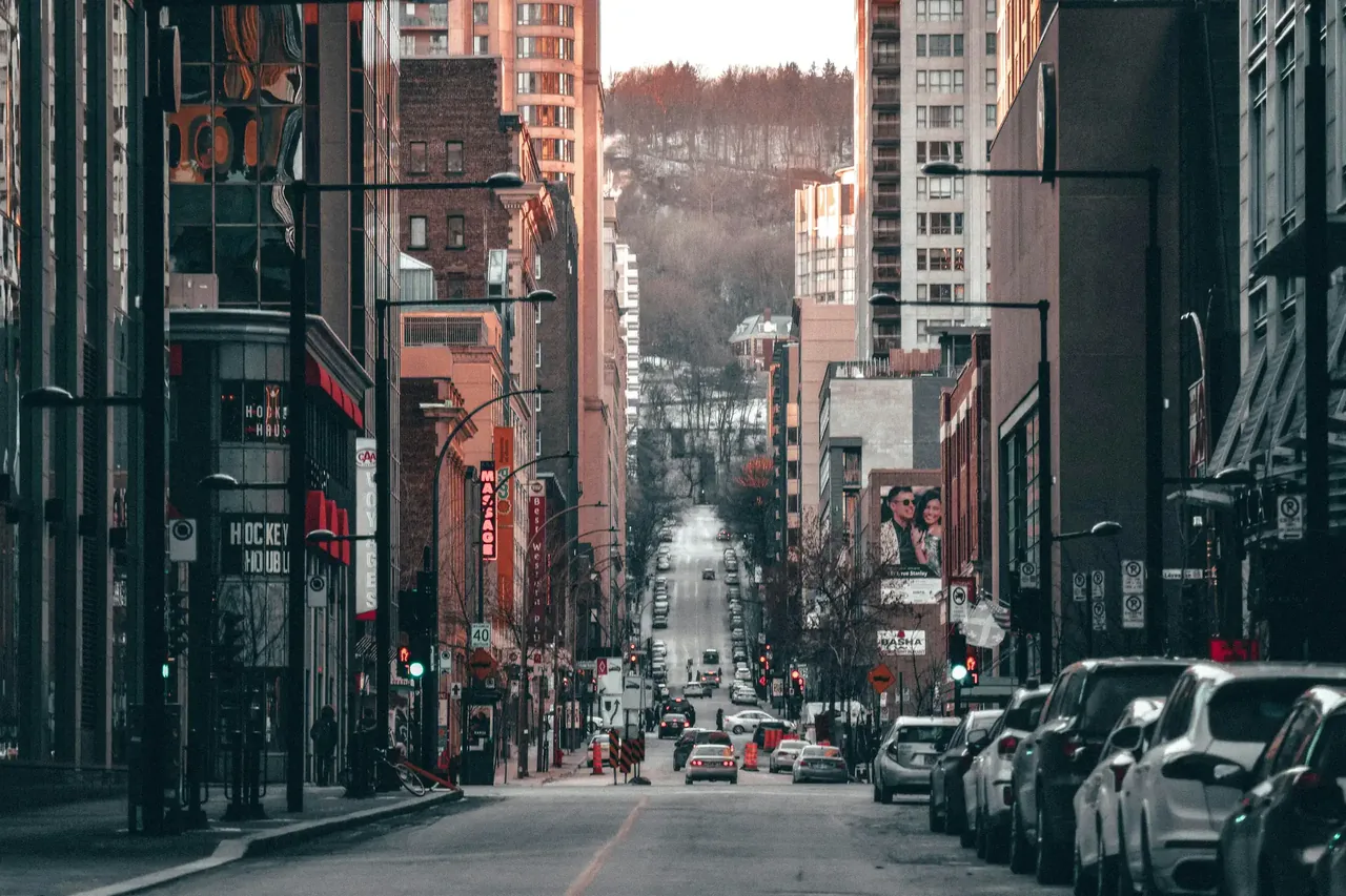A steep Montreal street of red-brick buildings with parked cars and the hill rising behind
