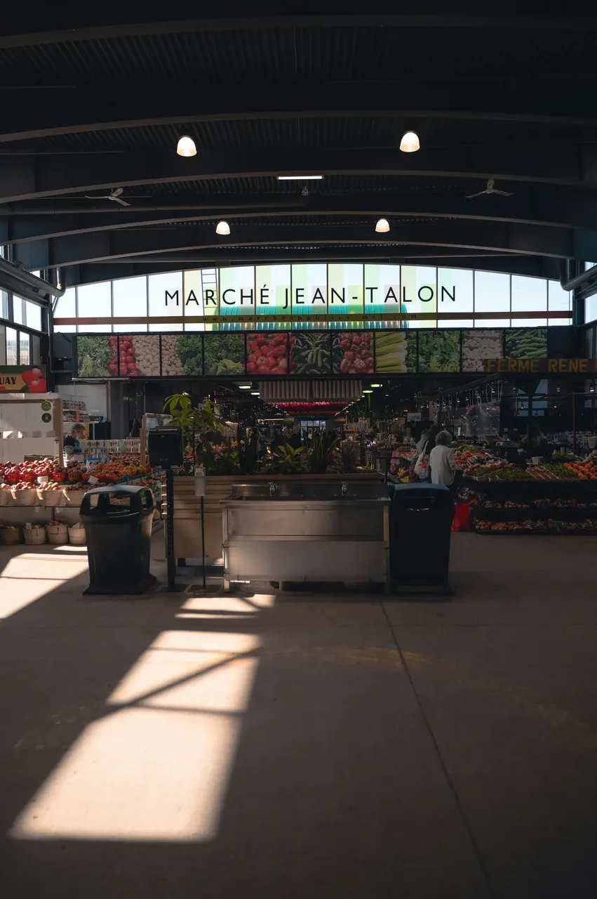 Inside the Jean-Talon market hall in Montreal, produce stalls under a high open roof