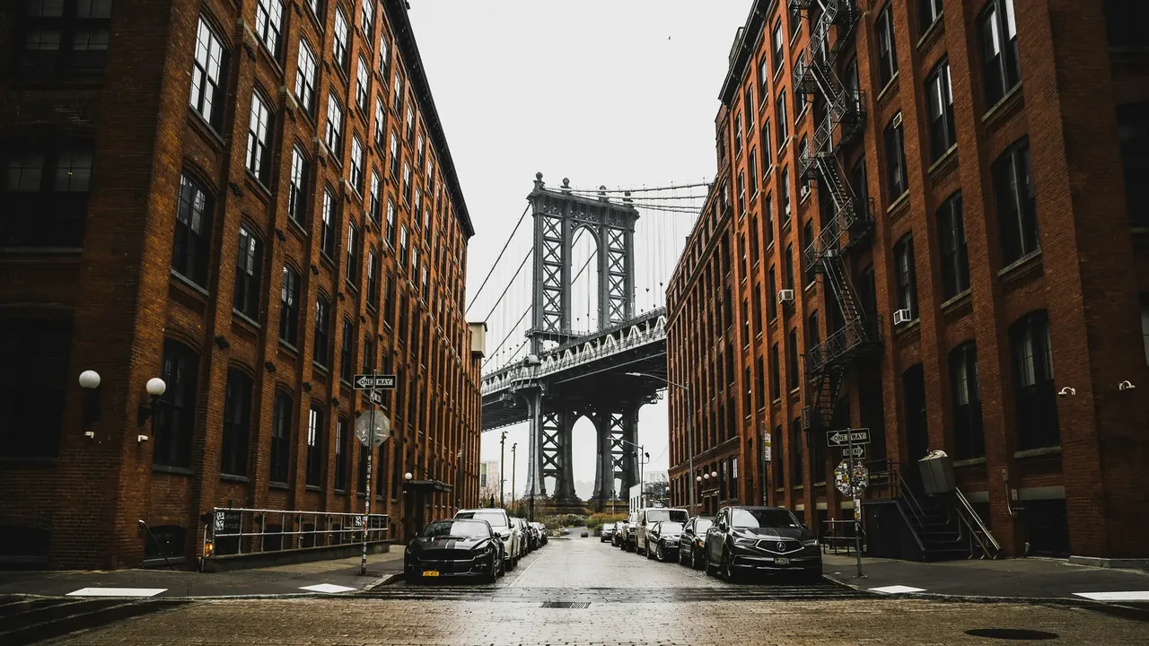 The Manhattan Bridge framed between brick warehouse buildings on a cobbled DUMBO street