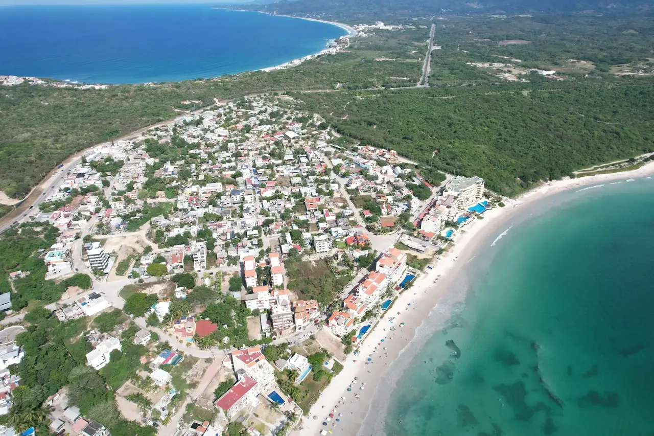 Punta Mita from the air, a low town on a headland between the ocean and a curving beach