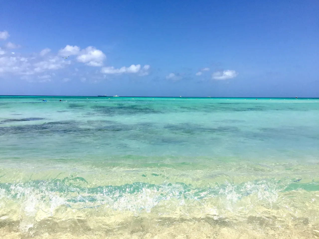 Flat turquoise Caribbean water under a wide sky with light cloud