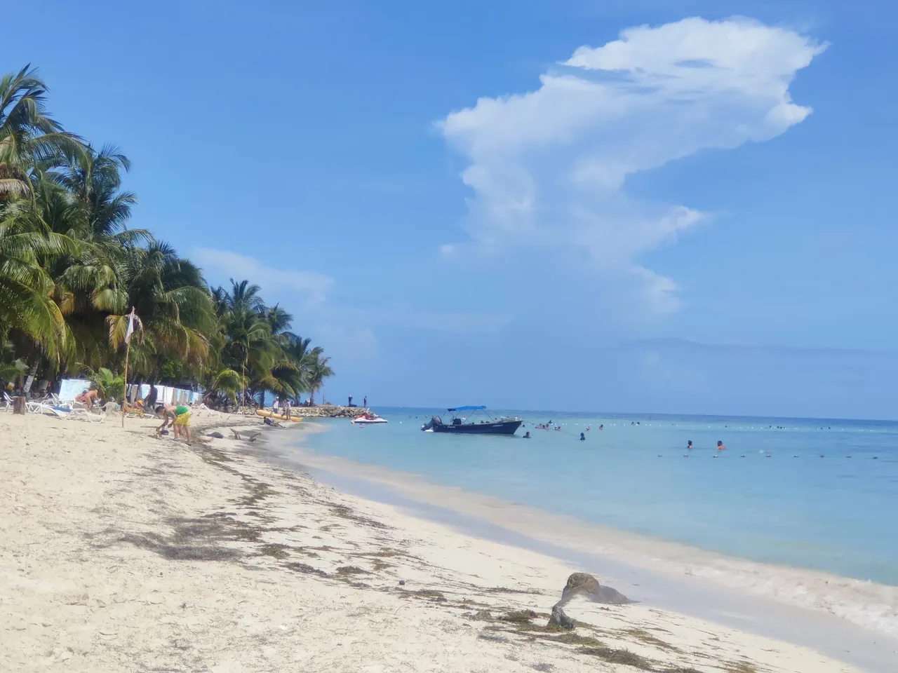 A palm-backed beach on San Andrés with a moored boat and people in the shallows